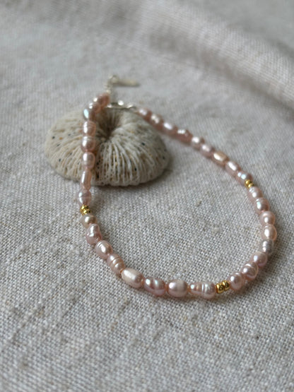 Pearl bracelet with gold accents on a textured fabric background