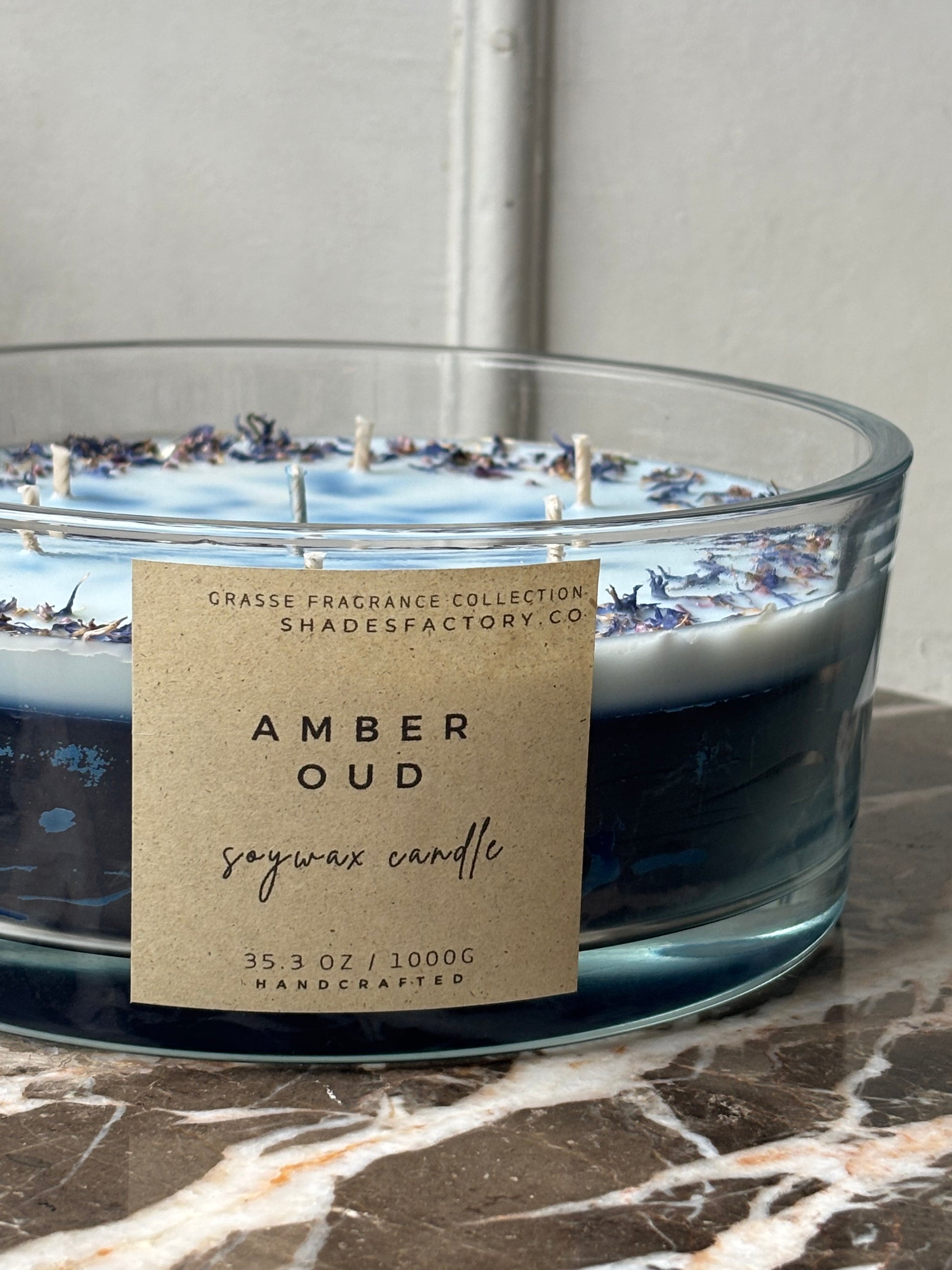 Candle with 'Amber Oud' label on a marble surface