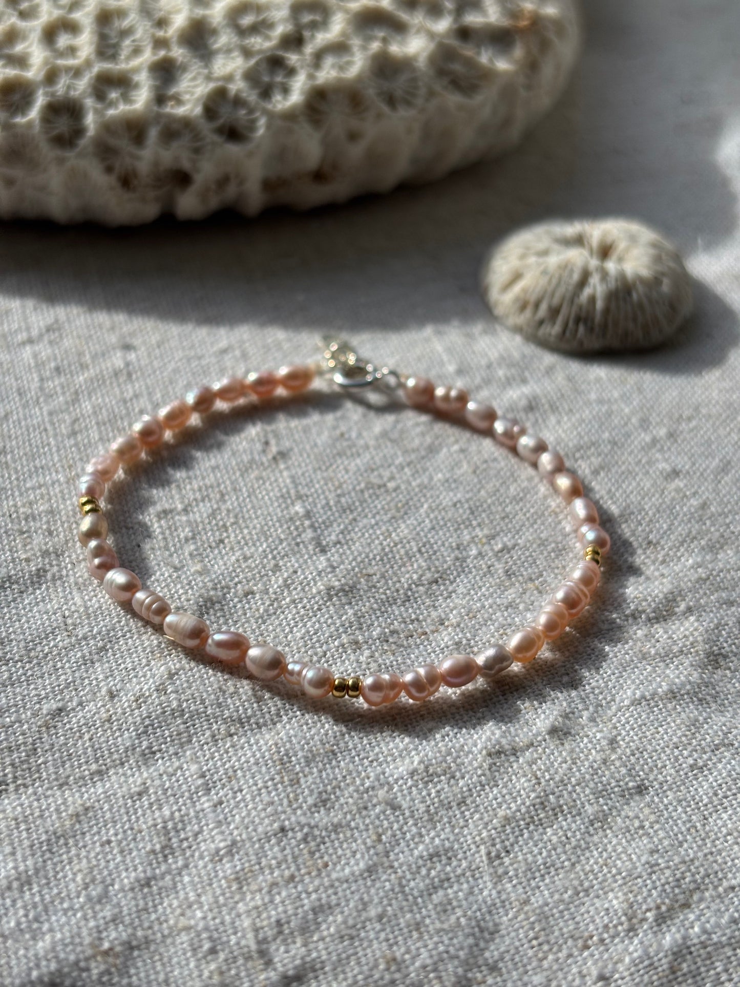 Pearl bracelet on a textured fabric surface with a natural stone.