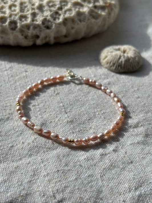Pearl bracelet on a textured fabric surface with a natural stone.