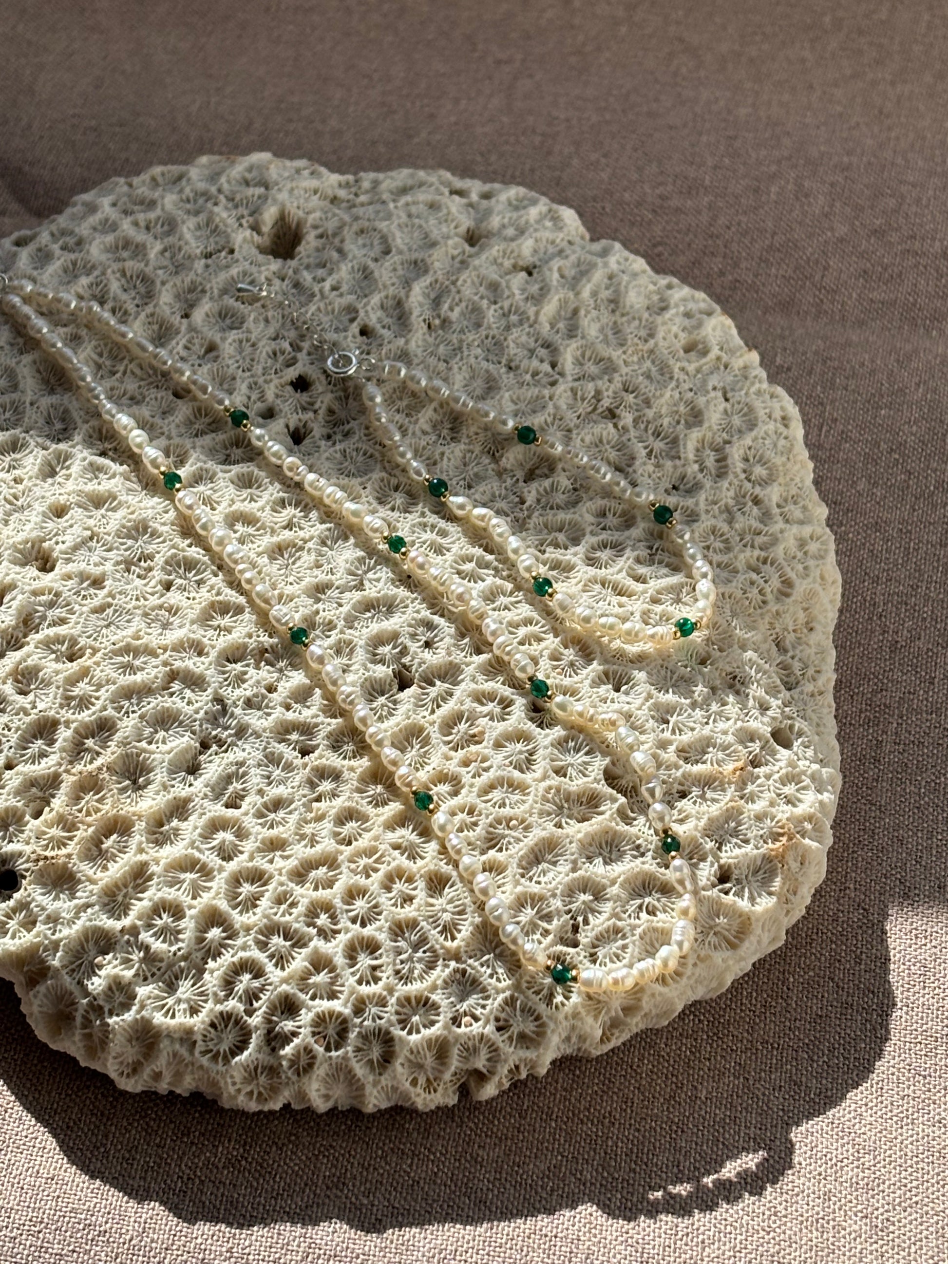Decorative stone with leaf design and green beads on a beige background