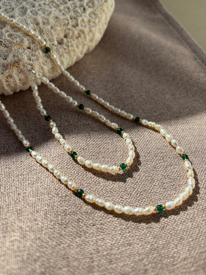 Pearl necklace with green beads on a textured surface