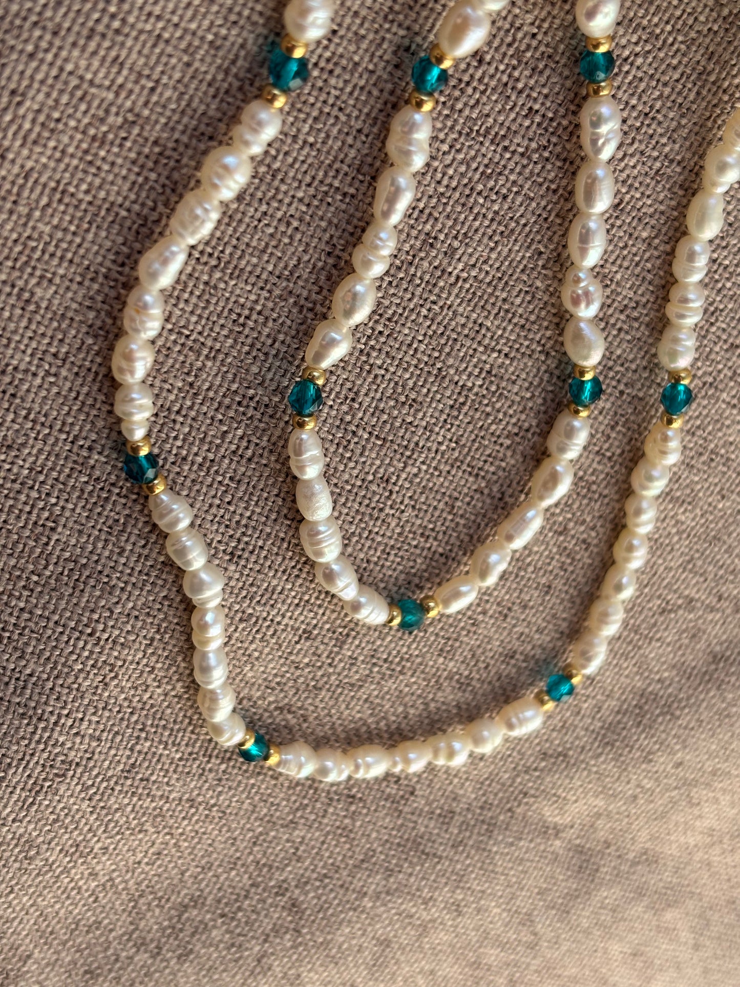 Pearl necklace with blue beads on a textured brown surface