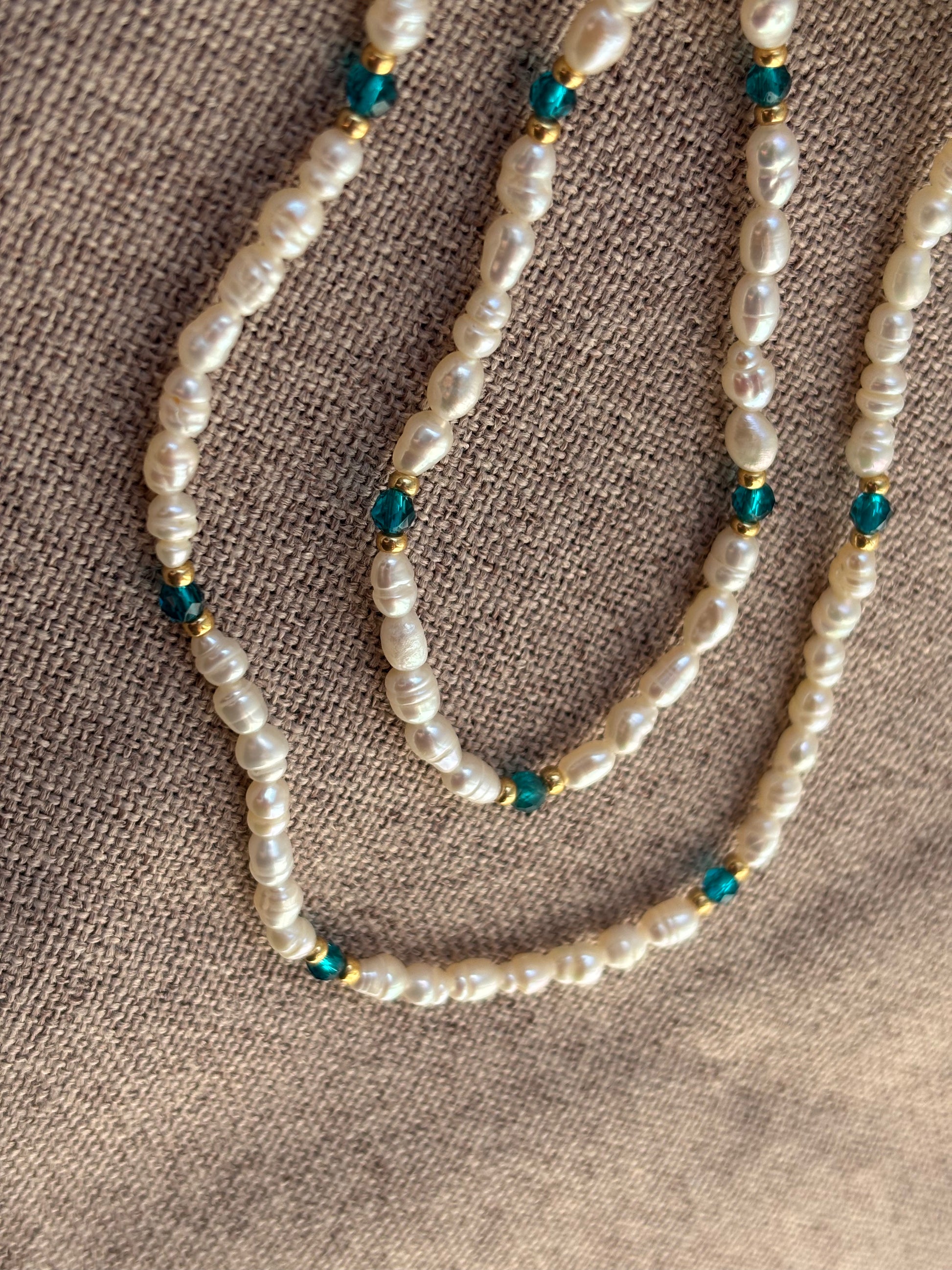 Pearl necklace with blue beads on a textured brown surface