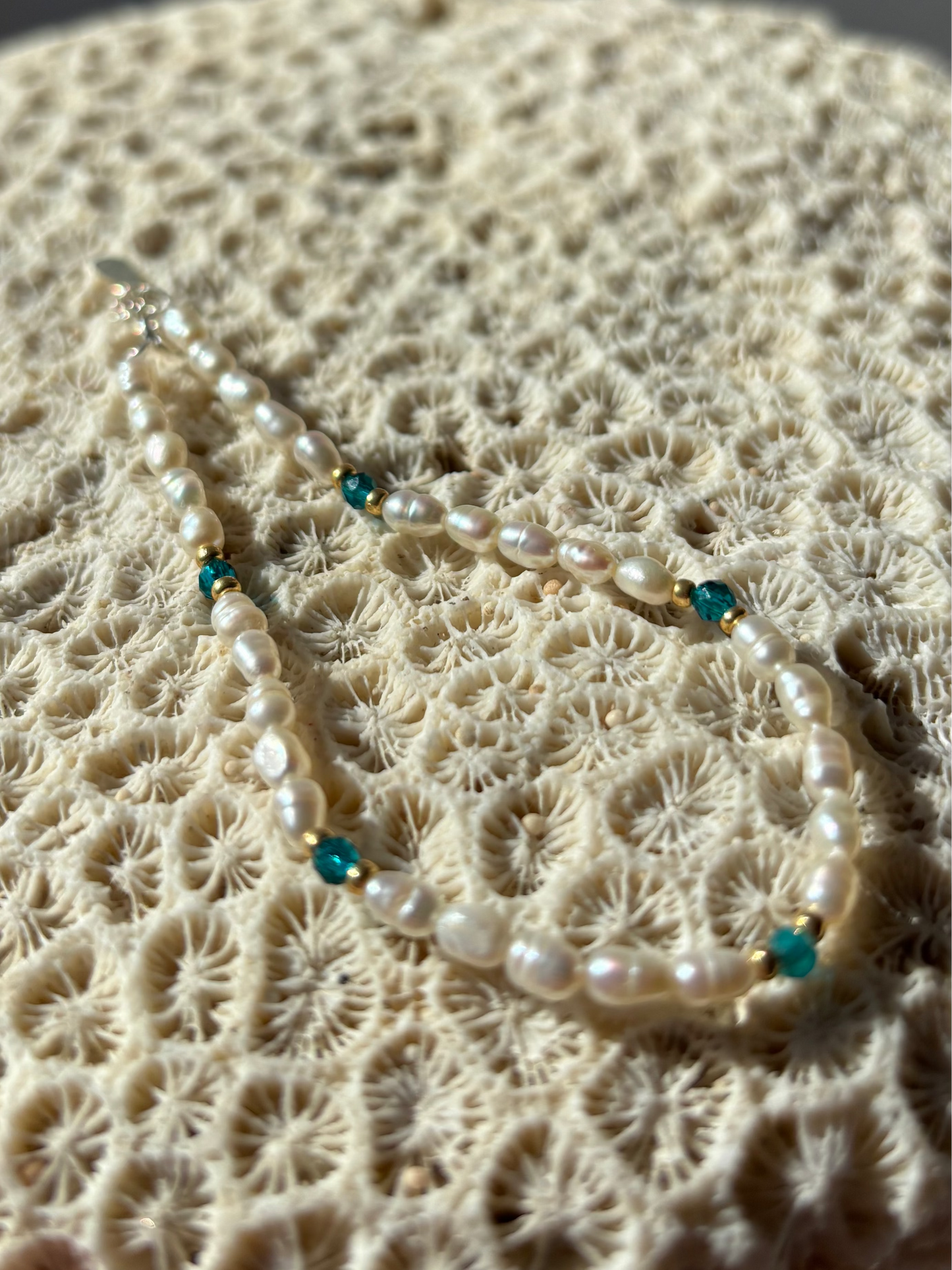 Pearl necklace with blue beads on a textured beige surface