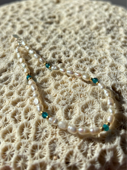 Pearl necklace with blue beads on a textured beige surface