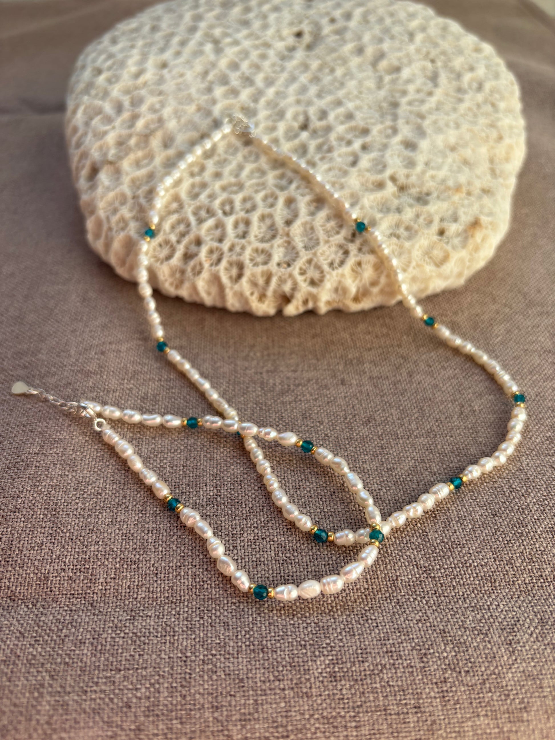 Pearl necklace with blue beads on a textured surface