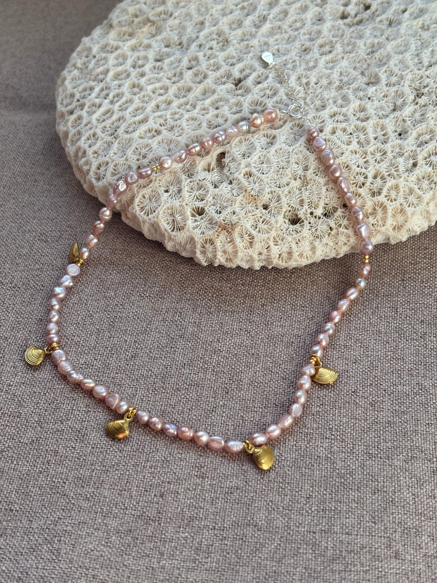 Pearl necklace with gold accents on a textured surface