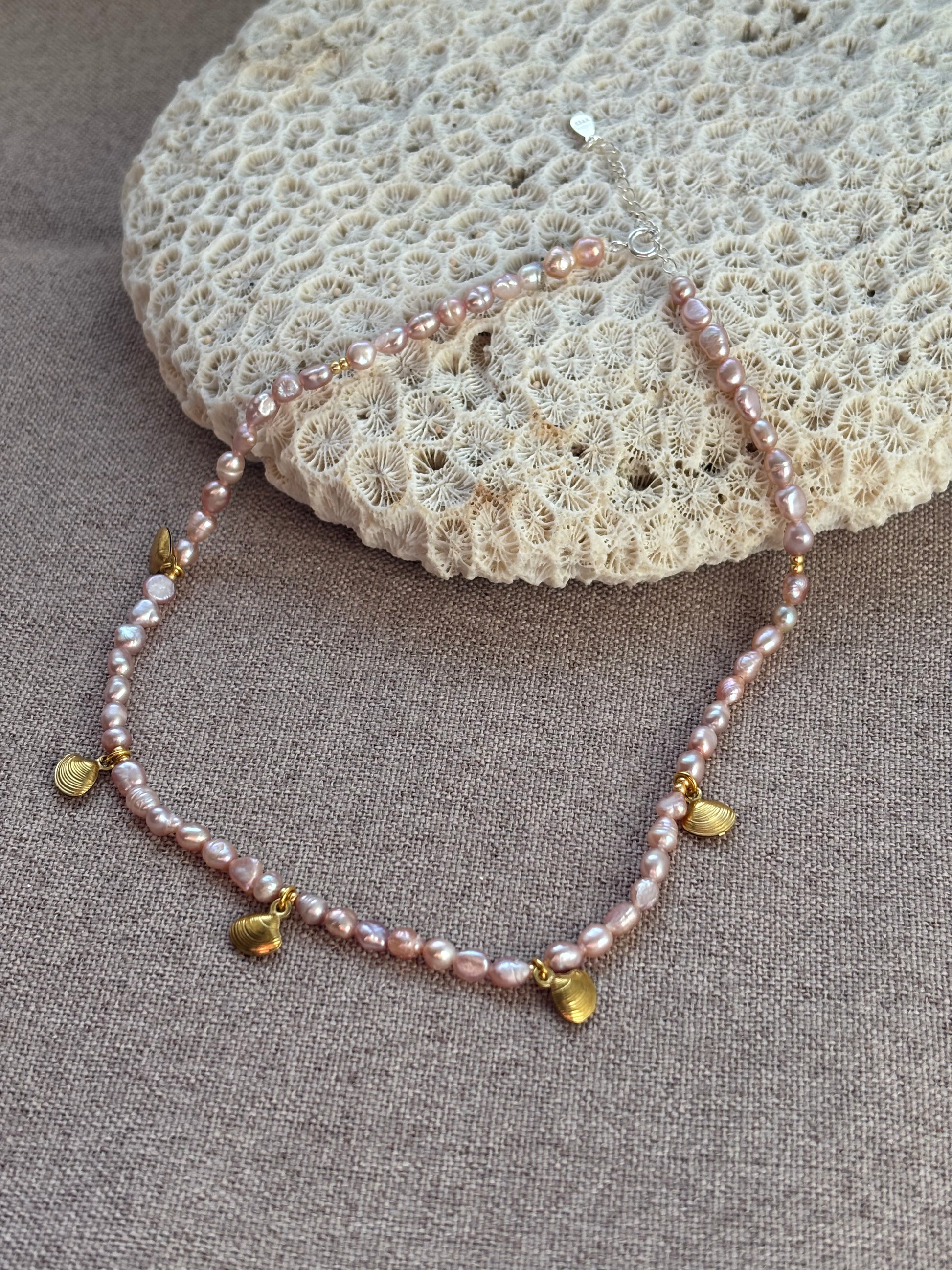Pearl necklace with gold accents on a textured surface