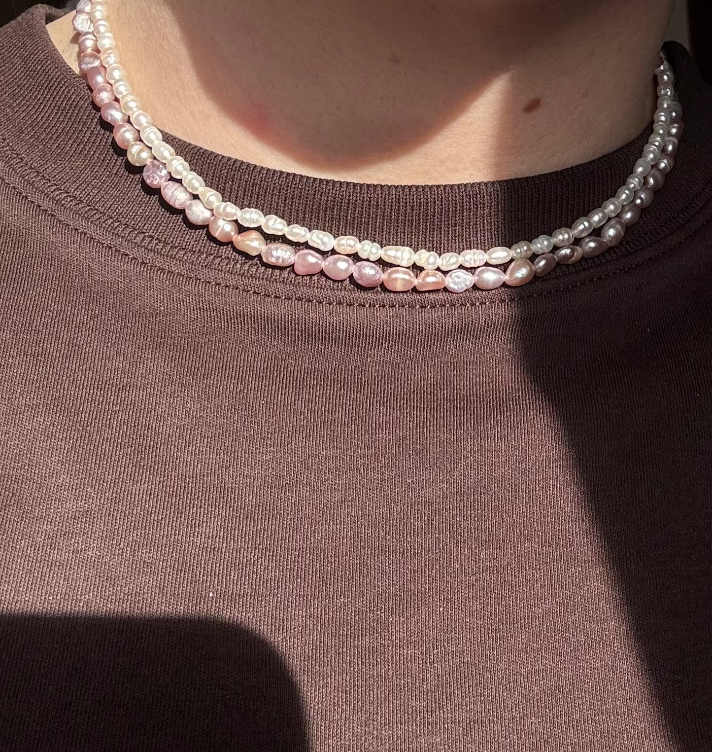 Person wearing a pearl necklace with a blurred background
