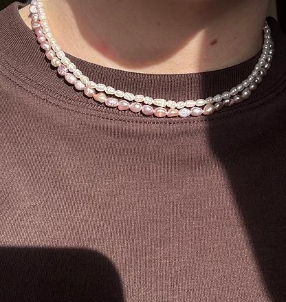 Person wearing a pearl necklace with a blurred background